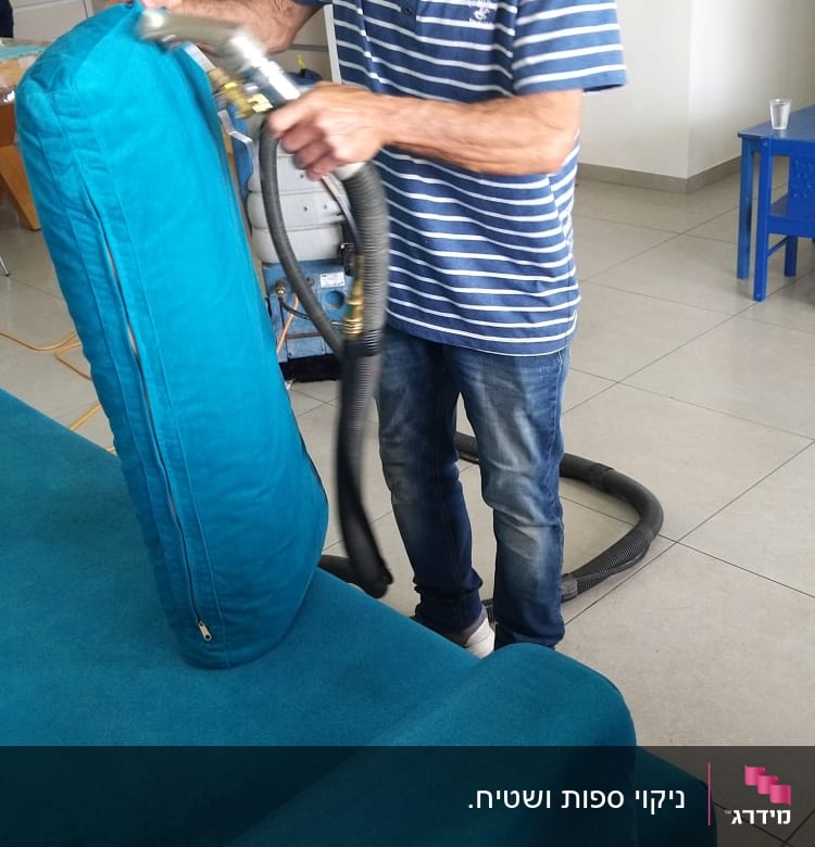 אדם מנקה ספה עם מכשיר שאיבה